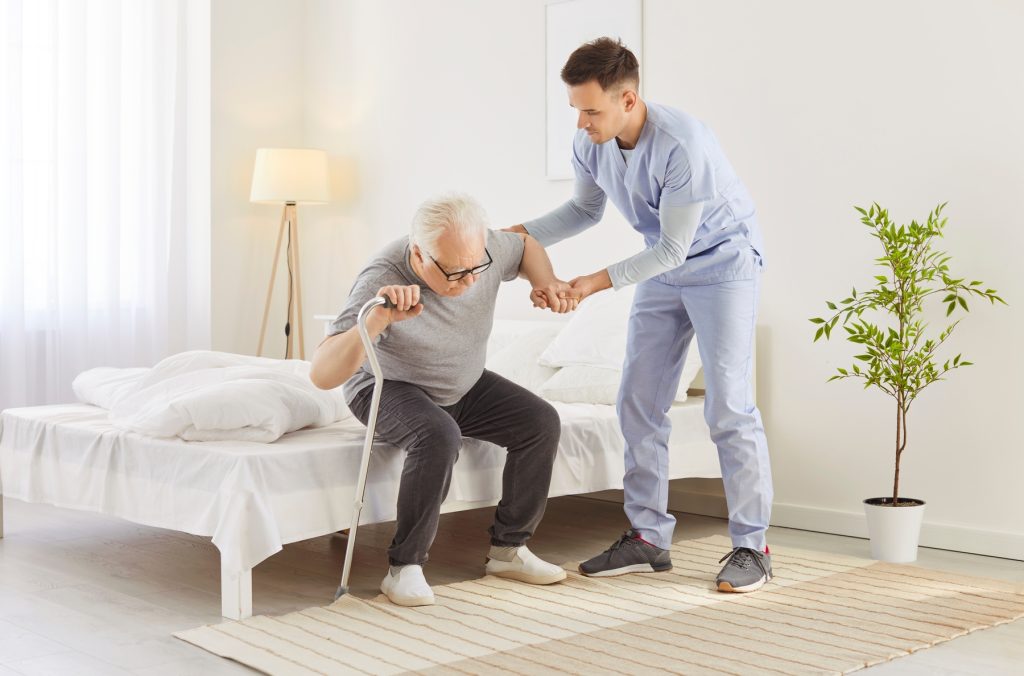 Caregiver,Helping,An,Elderly,Patient.,Young,Carer,In,A,Uniform